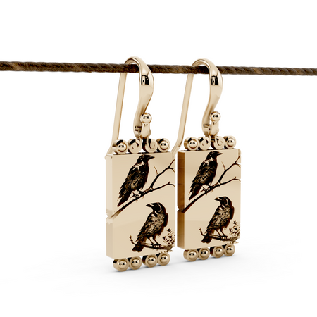 A pair of earrings with 2 crows sitting on branches in gold.
