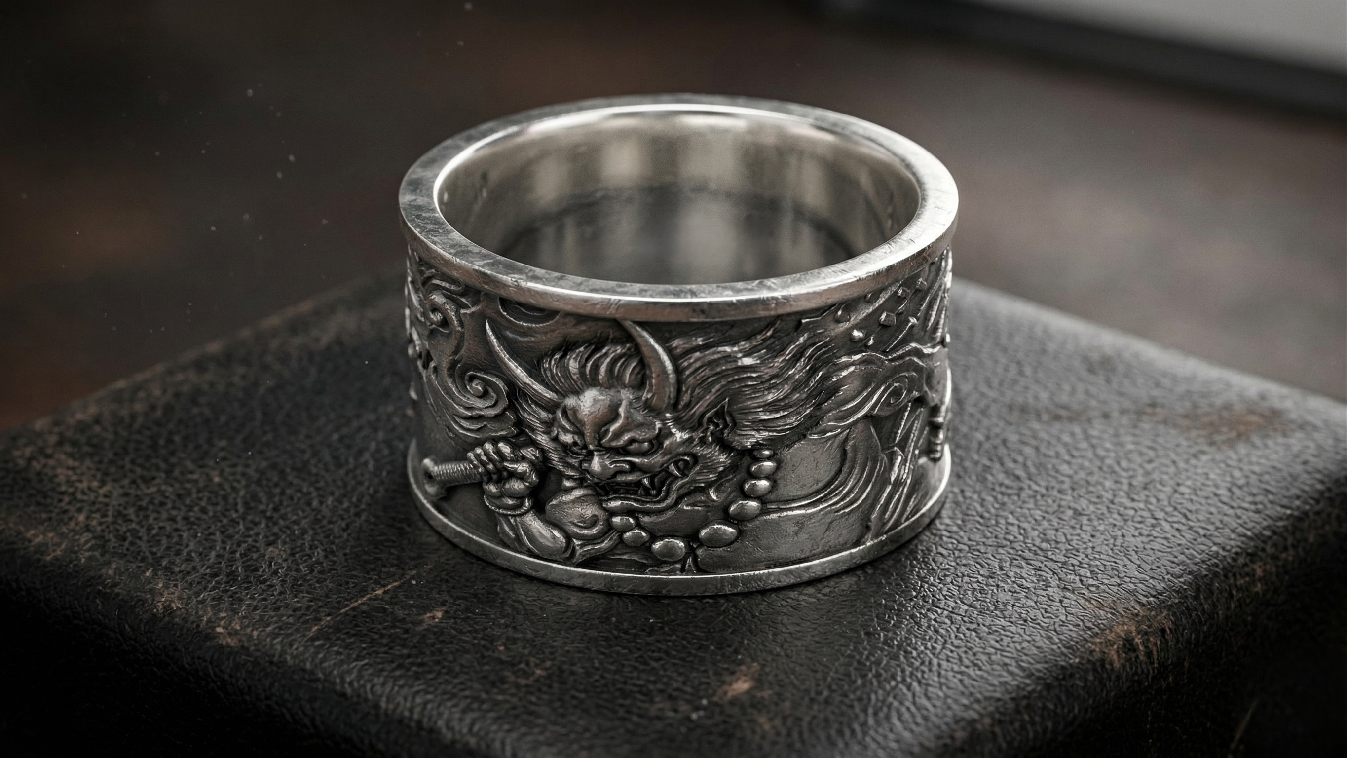 Silver ring with intricate designs on a dark surface