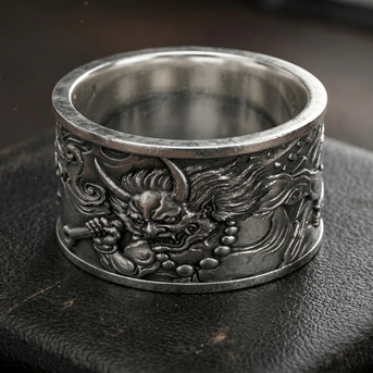 Silver ring with intricate designs on a dark surface